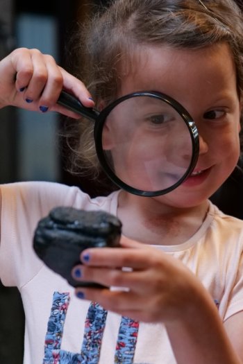 Photo of girls exploring coal with magnifying glasses