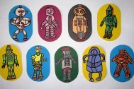 A photo of 9 pieces of coloured card, with a different robot cartoon drawn on each.
