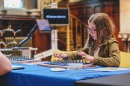 A photo of a child sat at a table, working on a technical skills board.