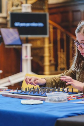 A photo of a child sat at a table, working on a technical skills board.
