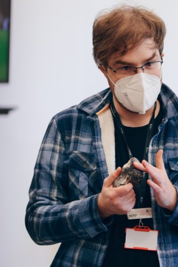 Demonstrator wearing a mask showing a mineral to a child